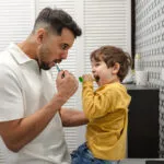 Father and son brushing teeth together in the bathroom